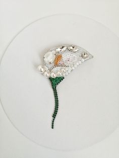 The calla is a symbol of purity. This brooch is perfect for a wedding in white color. The white calla beaded brooch is embroidered Swarovski pearls, Japanese seed beads Toho, crystals and rhinestone chains.Convo me please, if you want order flower brooch in any colors and in any quantity. Everything is handembroidered Veganfriendly, no animal fibers or materials used PACKAGINGThe product is packed in a stylish black cardboard box that can be used as a gift box. Color may vary slightly due to the Elegant Flower Shaped Beaded Brooches, White Pearl Brooches For Party, White Crystal Brooch With Rhinestones, White Pearl Party Brooches, White Crystal Brooches For Wedding, Elegant White Crystal Brooches, White Crystal Wedding Brooches, Elegant White Crystal Brooch, Calla Flower