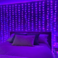 a bed with purple lights on the wall behind it and pillows in front of it