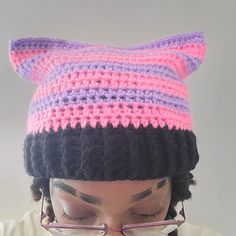 a close up of a person wearing glasses and a knitted cat hat