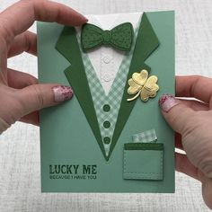 a person holding up a card with a green bow tie and shamrock brooch on it