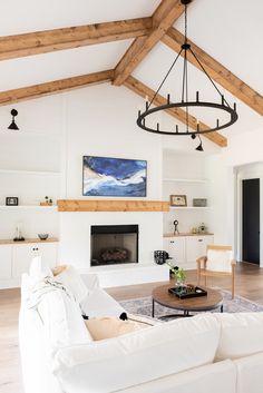 a living room filled with furniture and a fire place under a wooden beamed ceiling