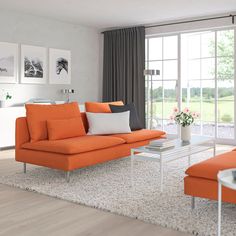 a living room with an orange couch and white coffee table in front of large windows