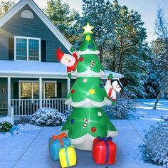 an inflatable christmas tree with presents and santa clause on it is standing in front of a house