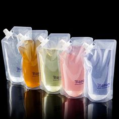 five bags with different colored liquids in them on a black surface, one is empty and the other has no lid