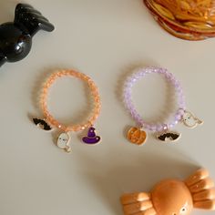 three bracelets with charms are sitting on a table next to a cat figurine