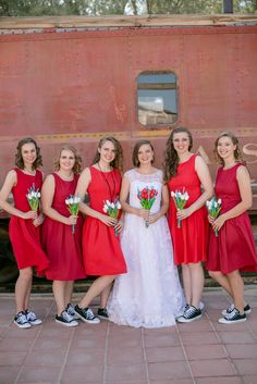 a group of women standing next to each other in front of a red train car