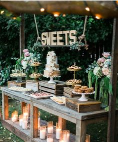 an outdoor dessert table with candles and cakes