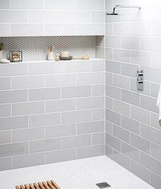 a white tiled bathroom with shelves above the shower