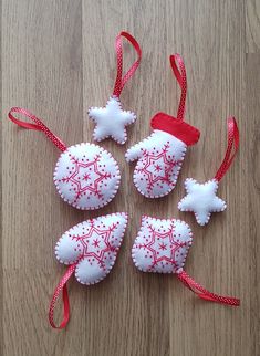 four christmas ornaments on a wooden surface with red ribbon and white snowflakes