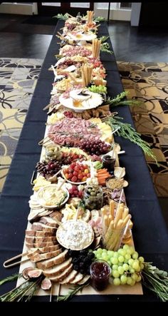 a long table filled with lots of different types of cheeses and crackers on it