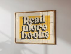 a framed poster that reads read more books in black and yellow on a white wall