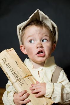 a young boy wearing a paper hat and holding a box