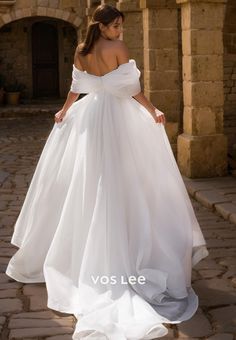 a woman in a white wedding dress standing on a stone walkway with her back to the camera