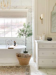 a bathroom with marble walls and flooring, a white bathtub next to a window