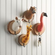 four animal key chains hanging on a wall with wood slices attached to it's hooks