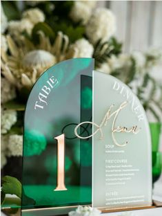 the table number is displayed on an acrylic stand with flowers in the background