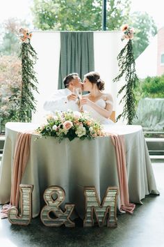 the bride and groom are kissing at their wedding reception table with mr and mrs letters