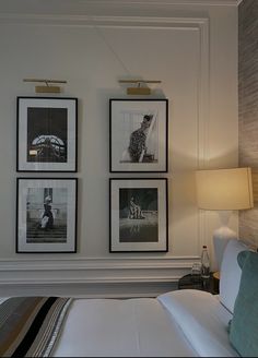 three framed pictures hang on the wall above a bed in a room with white walls