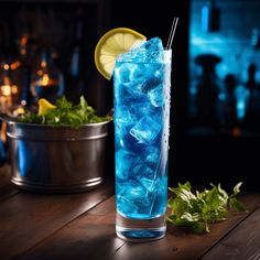 a tall glass filled with blue liquid and ice next to a metal bowl full of mint leaves