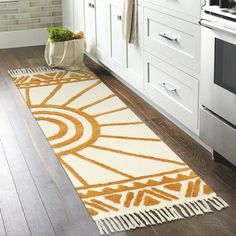 an orange and white rug in a kitchen next to a stove top oven on a hard wood floor