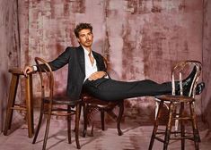 a man in a suit and tie sitting on top of a chair with his legs crossed