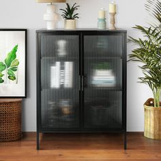 a black cabinet sitting next to a potted plant on top of a wooden floor