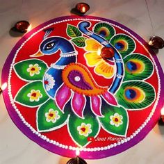 a colorfully decorated plate with candles on the floor next to it and an image of a peacock