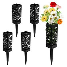 four black metal vases with flowers in them