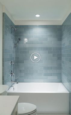 a white toilet sitting next to a bath tub in a bathroom under a light fixture