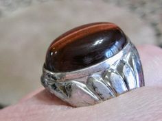 "Art deco man's statement ring: ~ Features a large bezel oval rare chocolate brown tiger's eye cabochon gem  ~ Stylized art deco Egyptian revival lotus flower design on both sides ~ I am guessing this to be early 1920's in age ~ Tiger's Eye is known to have powerful metaphysical or healing properties such as releasing fear and anxiety, aids harmony and balance, stimulates taking action, helps you to make decisions with discernment and understanding, and can uncloud your emotions. Ready and waiti Egyptian Lotus, Mans Ring, Art Deco Egyptian, Stylized Art, Lotus Flower Design, Brown Tiger Eye, Lotus Design, Egyptian Revival, Sterling Silver Mens