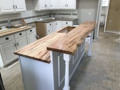 a kitchen with white cabinets and wooden counter tops in the middle of the flooring