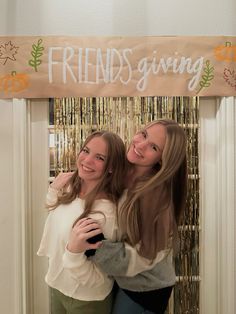 two girls hugging each other in front of a friend's giving sign