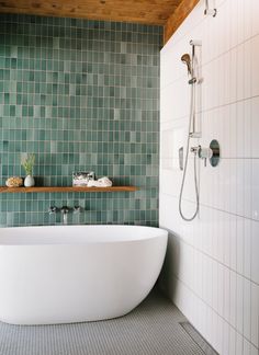 a white bath tub sitting in a bathroom next to a walk in shower and tiled walls