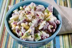 a blue bowl filled with macaroni salad on top of a striped table cloth