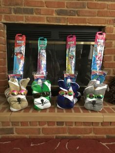 four small stuffed animals are lined up in front of a fire place with masks on them