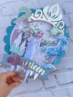 someone holding up a frozen princess cutout with snowflakes and glitters on it