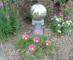 a mirror ball sitting on top of a metal object in the middle of some flowers