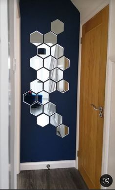 a room with blue walls and white hexagonal mirrors on the wall, along with a wooden door