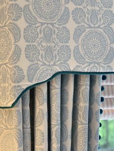 a window with blue and white curtains in front of a window sill that has an ornate pattern on it