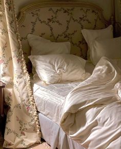 an unmade bed with white sheets and pillows