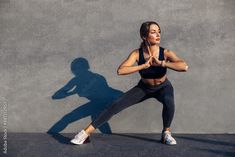 a woman in black sports bra top and leggings doing yoga exercises with her shadow on the wall