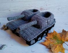 two crocheted slippers sitting on top of a wooden table next to leaves