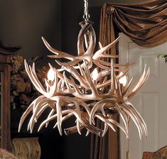 a chandelier made out of antlers hanging from a ceiling in a living room