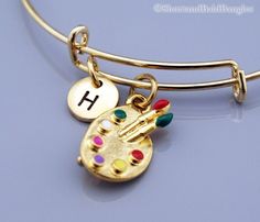 "❖ Paint palette charm: Gold plated and enamel painted. Approx: 3/4 X 1/2\" ❖ Hand Stamped Initial Charm - Antique gold pewter 3/8\" (9mm) ❖ Bangle: Gold plated metal (Expandable) Dimension: Approx. 2.5\" (6.4 cm) - Expands to 3\" (7.6 cm) ❖ Click below for Paint palette bangle in silver: https://www.etsy.com/listing/1157042331 ❖ Add a birthstone or freshwater pearl $3.50 each: https://www.etsy.com/listing/110444872 ❖ Additional Hand Stamped Initial charms $4.50 each: https://www.etsy.com/listin Artsy Adjustable Gold Bracelets, Artsy Adjustable Gold Bracelet, Hand Painted Gold Bracelets For Gift, Gold Hand Painted Bracelets As Gift, Gold Hand Painted Bracelets For Gift, Adjustable Artsy Gold Bracelet, Adjustable Hand Painted Gold Bracelet, Thor's Hammer Necklace, Painters Palette