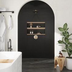 a white bath tub sitting next to a green plant in a bathroom under a black door