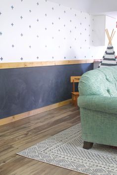 a green chair sitting on top of a wooden floor next to a blackboard wall