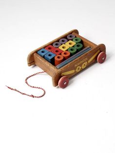 a wooden toy that has some colored blocks on it's back and is attached to a string