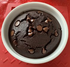 a chocolate cake in a white bowl on a red table