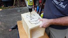 a man is using a drill to cut out a face on a piece of wood