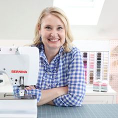 a woman sitting at a sewing machine smiling